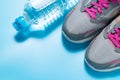 Sport pink shoes and bottle of water on blue background with copyspace for your text. Concept healthy lifestyle and diet Royalty Free Stock Photo