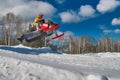 Sport red snowmobile jump. Sunny winter day with blue sky. Concept quick movement.