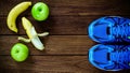 Sport shoes, apples and bananas on a wooden background. Sport Royalty Free Stock Photo