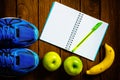 Sport shoes, apples and bananas on a wooden background. Sport Royalty Free Stock Photo