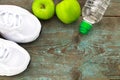 Sport shoes, apples, bottle of water on wooden background. Conc Royalty Free Stock Photo