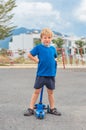 Sport smiling freckled blond boy male child happy facial expressions, cunning funny mischievous, stand hold kick scooter Royalty Free Stock Photo