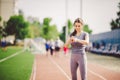 Sport and technology. beautiful young whiteskinned woman with ponytail at running stadium in front of workout uses a sporty smart Royalty Free Stock Photo