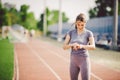 Sport and technology. beautiful young whiteskinned woman with ponytail at running stadium in front of workout uses a sporty smart Royalty Free Stock Photo