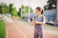 Sport and technology. beautiful young whiteskinned woman with ponytail at running stadium in front of workout uses a sporty smart