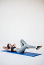 Sport tutorials for beginners to warm up. The attractive athletic trainer is lying on the mat and doing bicycle crunches