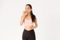 Sport, wellbeing and active lifestyle concept. Smiling satisfied cute asian fitness girl eating green apple with Royalty Free Stock Photo