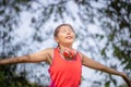 Sport woman breathing deeply fresh air with arms raised outdoor in a forest with blurred background Royalty Free Stock Photo