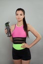 Sport woman brunette holding proteine shake or water bottle on gray background