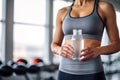 A sport woman in gray activewear holding water bottle in her hands at the gym, fitness and healthy lifestyle concept, Royalty Free Stock Photo