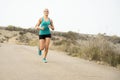 Sport woman running on asphalt dirty road with dry desert landscape background training hard