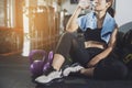 Sport woman sitting and resting after workout or exercise in fitness gym with protein shake or drinking water on floor. Relax Royalty Free Stock Photo