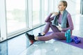 Sport woman sitting and resting after workout or exercise in fitness gym with protein shake or drinking water on floor. Relax Royalty Free Stock Photo
