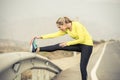 Sport woman stretching leg muscle after running workout on asphalt road with dry desert landscape in hard fitness training session Royalty Free Stock Photo