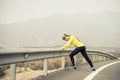 Sport woman stretching leg muscle after running workout on asphalt road with dry desert landscape in hard fitness training session Royalty Free Stock Photo