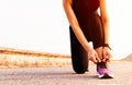 Sport woman tying shoelace while running, sunset on the long road Royalty Free Stock Photo