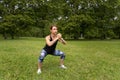 Sport woman wearing exercise suit doing stretching fitness exercise in city park at green grass Royalty Free Stock Photo