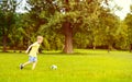 Sporting boy plays football in sunny park Royalty Free Stock Photo