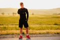 Sportiv man runner resting after training outdoors, looking watch with a beautiful background