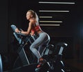 Sportive blonde woman working out on an exercise bike in modern fitness center. Fitness lifestyle in sport club.