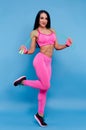 Sportive brunette girl in the pink sportswear with skipping rope