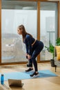 Sportive brunette practices exercises with dumbbell on mat