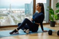 Sportive brunette with water bottle in hand sits on mat