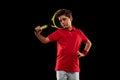 Cropped portrait of boy, tennis player in motion, training isolated over black backgound Royalty Free Stock Photo