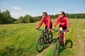 Sportive couple riding bike in summer meadow