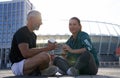 Sportive fit couple having conversation while sitting outdoors after morning workout on a sunny summer day Royalty Free Stock Photo