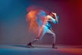 Sportive girl with short hair dancing hip-hop in stylish sportswear in colorful neon light at dance hall. Long exposure Royalty Free Stock Photo