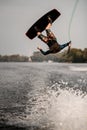 sportive guy doing extreme high jump on wakeboard over splashing river wave Royalty Free Stock Photo