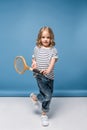 sportive little girl standing and holding tennis raquet while looking