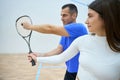 Sportive man instructor teaching woman squash emphasizing hitting skills