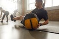Sportive man using exercise ball while having workout at industrial gym. Group training, teamwork concept