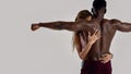 Sportive mixed race woman embracing, touching muscular african american man back while posing together isolated over