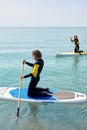 Sportive people standing paddling away on stand up paddleboarding at sea on blue water Royalty Free Stock Photo