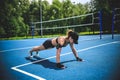 Sportive woman doing push-ups on the blue tennis court in Moscow Yauza park