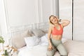Sportive woman in happy mood getting ready for morning workout, sitting on a bed. Beautiful female preparing to do Royalty Free Stock Photo