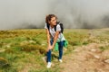 Woman hiker climbing on mountain surrounded with clouds in Carpathians. Tired traveler with backpack resting