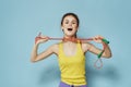 Sportive woman holding a skipping rope yellow tank top exercise gymnastics blue background Royalty Free Stock Photo