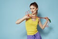 Sportive woman holding a skipping rope yellow tank top exercise gymnastics blue background Royalty Free Stock Photo