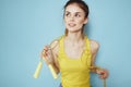 Sportive woman holding a skipping rope yellow tank top exercise gymnastics blue background Royalty Free Stock Photo