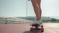 sportive woman legs on longboard, femlae skater is riding skateboard on city street, closeup view