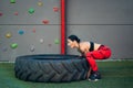 Sportive woman lifting a truck wheel in a gym Royalty Free Stock Photo