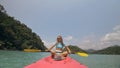 Sportive woman rows pink plastic canoe along sea water. Positive sports girl hand padding on kayak, front view. Royalty Free Stock Photo