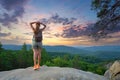 Sportive woman walking alone on hillside trail. Female hiker enjoying view of evening nature from rocky cliff on Royalty Free Stock Photo