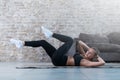 Sportive young lady doing crisscross crunch exercise lying on a rug at modern studio Royalty Free Stock Photo