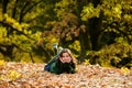 Portrait of a smiling teenager. Young teen girl looking to camera. Cute teenage girl lying on autumn maple leaves at