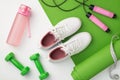 Sports accessories concept. Top view photo of white sneakers pink bottle of water green sports mat dumbbells skipping rope and Royalty Free Stock Photo